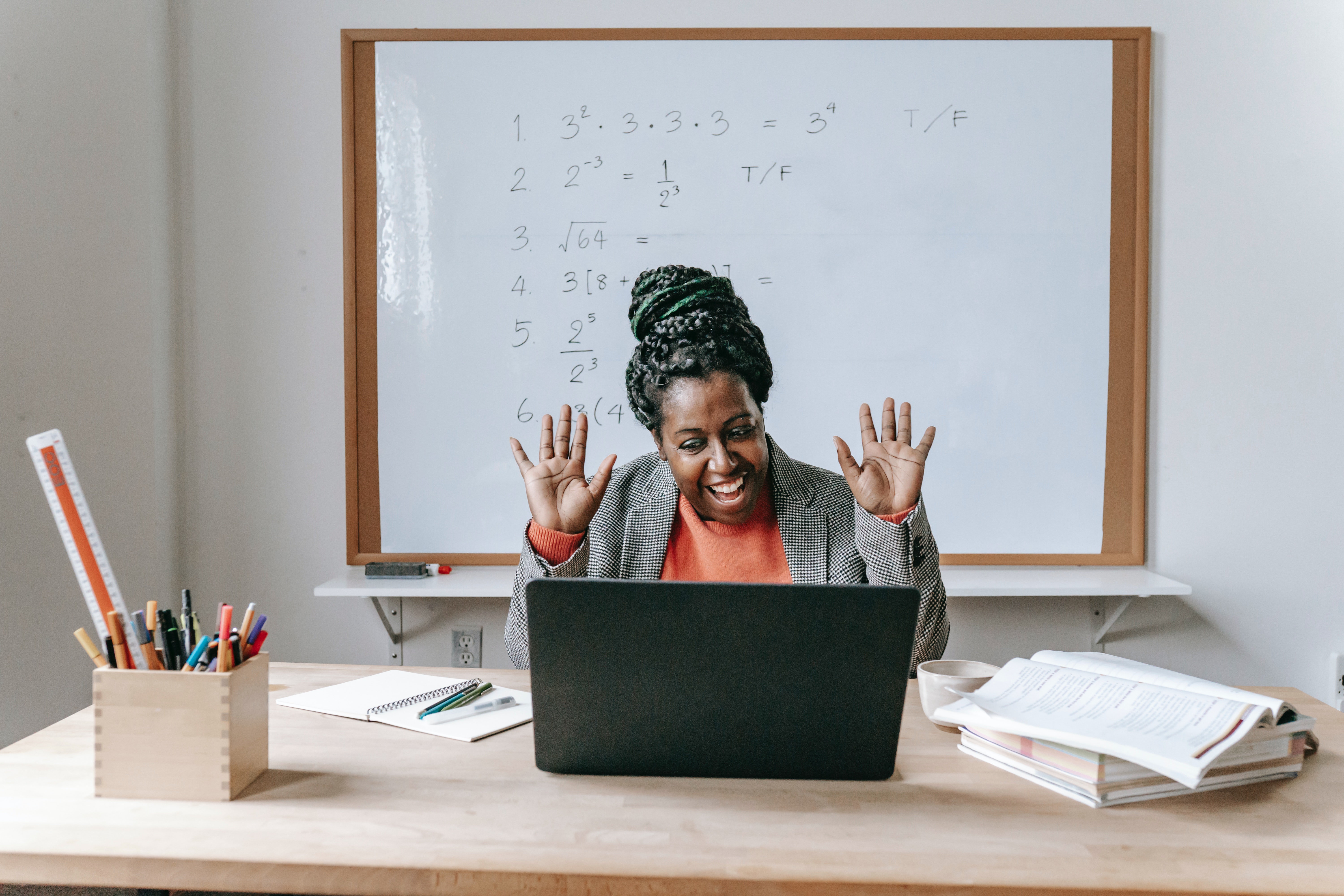 Smiling woman waving at a computer screen